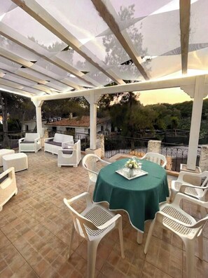 An outdoor patio with white wicker furniture, a round table with a green tablecloth, and a pergola overhead. - House / Villa - Perd'e'Sali (Pula)