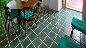 Cocina compacta con comedor, refrigerador y ventana con cortinas.