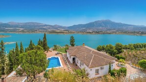 Une maison avec une piscine, entourée d’arbres, et offrant une vue sur un lac et des montagnes.