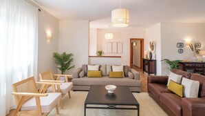 Un salon comprenant un canapé, deux fauteuils, une table basse et une table à manger.