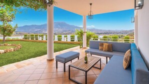 Une terrasse avec un canapé, une table et une bouteille de champagne.