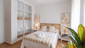 Une chambre d’hôtel avec un lit, une armoire, deux tables de chevet et une plante en pot.