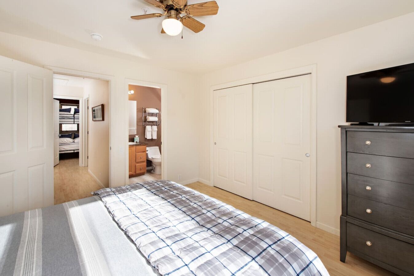 A bedroom with a bed, a dresser, a closet, and a television.