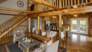 Un vaste espace de vie agrémenté d’un escalier en bois, d’un coin salon confortable et d’une cuisine située au fond de la pièce.
