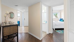 Un pasillo que conduce a un dormitorio con una cama, un aparador y un espejo.