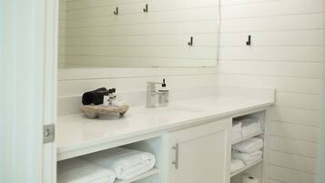 A bathroom with a white sink, mirror, and shelves with towels.