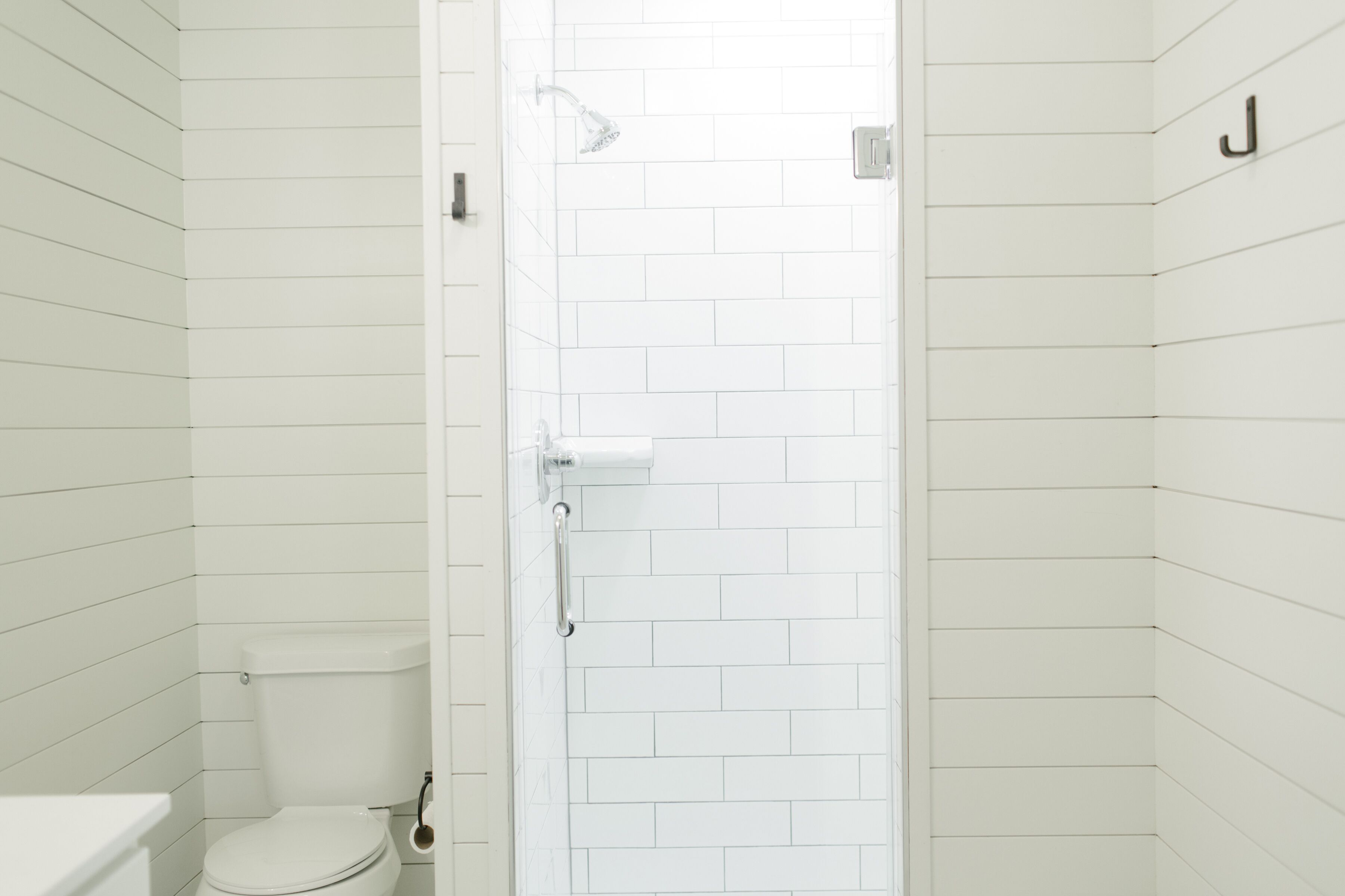 Un bagno con pareti piastrellate di bianco, un WC e una zona doccia.