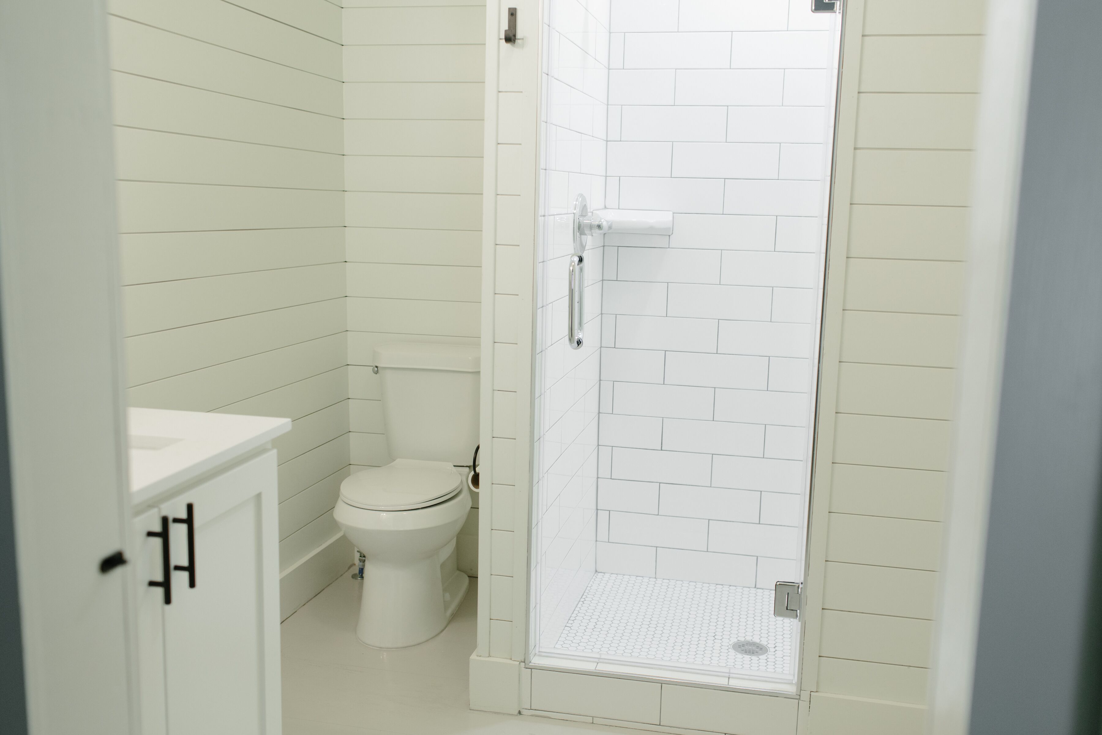 A bathroom with a toilet, a shower with a glass door, and a white sink.