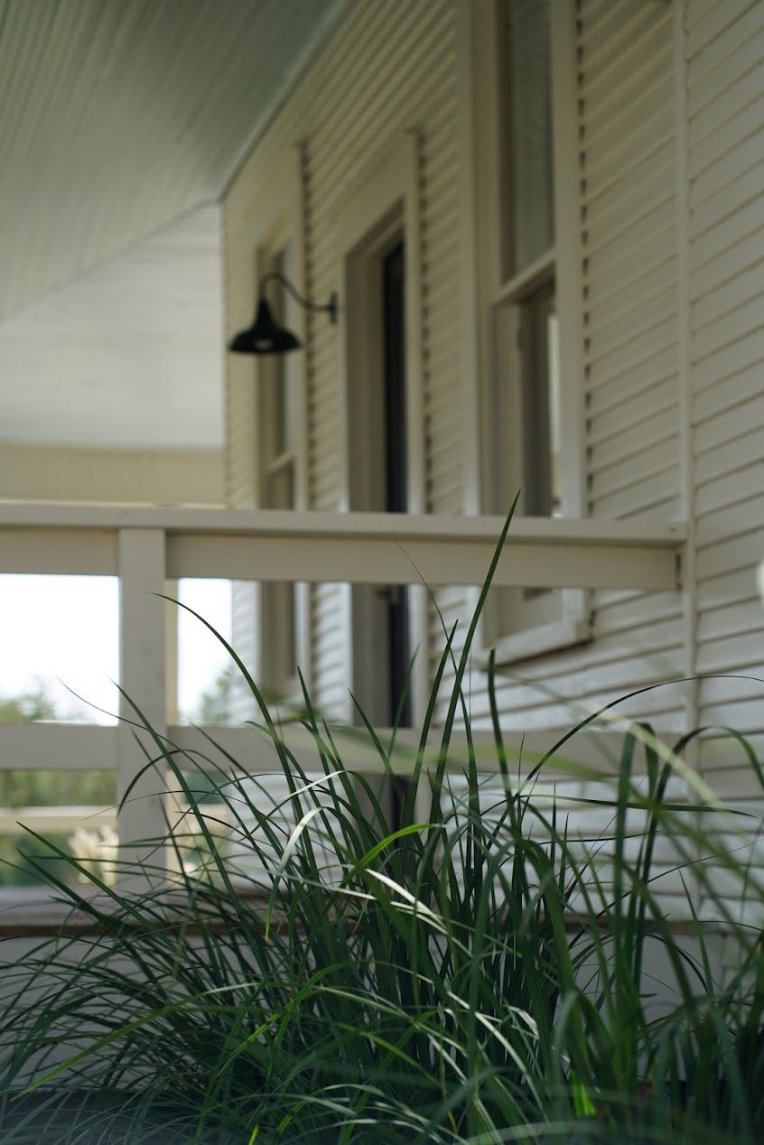 A porch with a railing, a hanging light fixture, and a window.