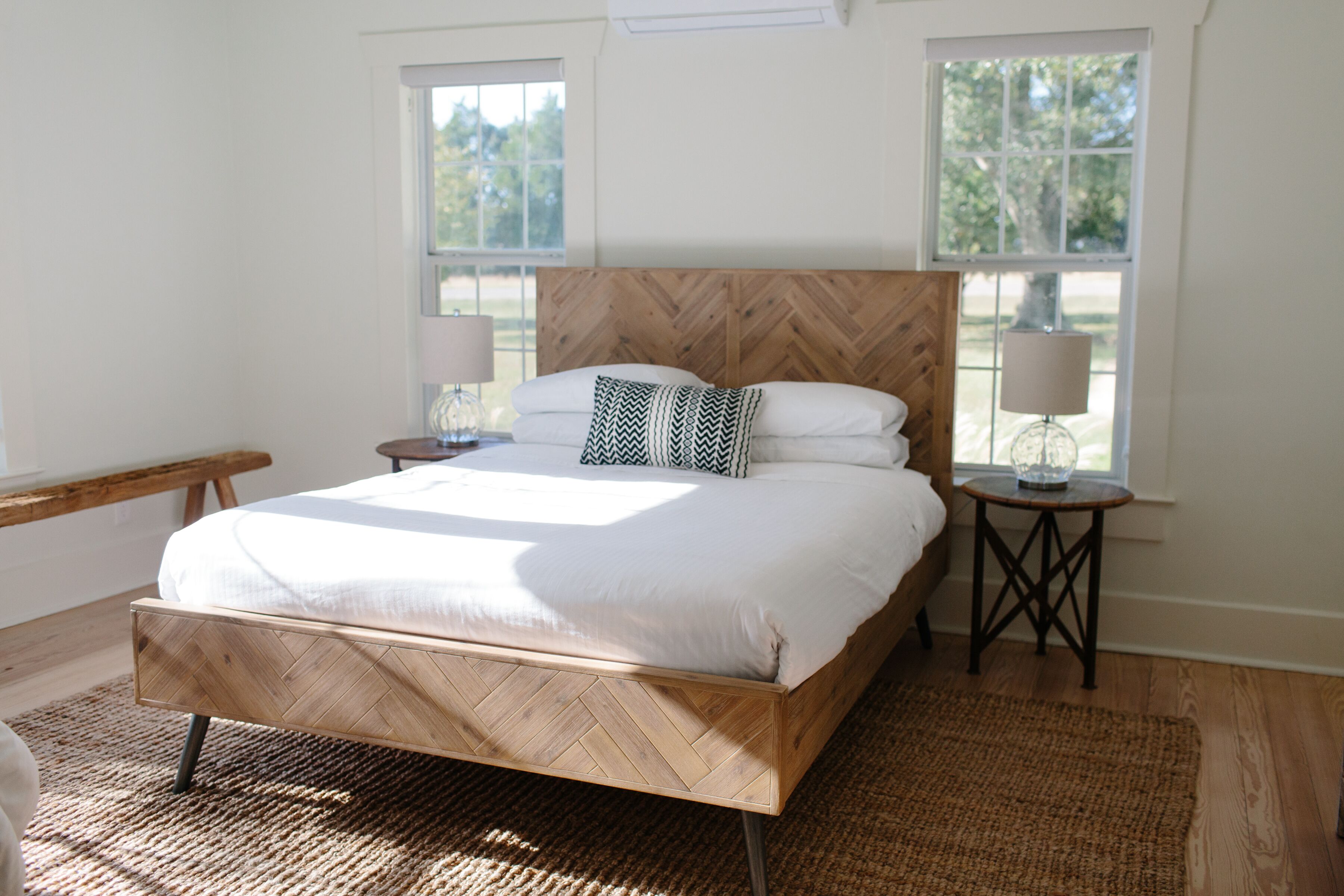 Una camera da letto con un letto di legno, due comodini e un'ampia finestra.