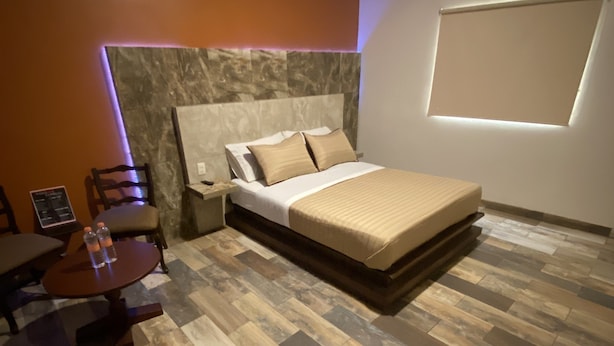 Un dormitorio moderno con una cama grande, suelo de madera y una pequeña mesa con sillas.