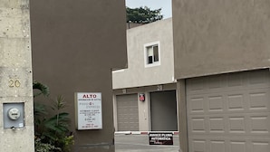 Entrada a un aparcamiento con dos garajes, un cartel que indica 'AVANCE PLUMA AUTOMATICA', señalizando un sistema de estacionamiento automático, y un cartel de 'PASSION EXPRESS' para servicio de chófer.