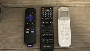 Tres controles remotos sobre una superficie de madera.