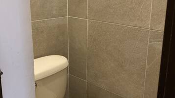 Un baño pequeño y cerrado con inodoro y un cubo de basura.
