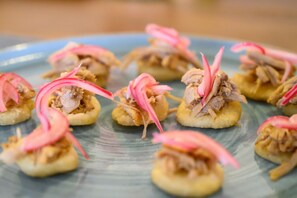 A plate of appetizers with shredded meat and pink garnish.