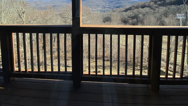 Une terrasse en bois avec une balustrade donnant sur un paysage montagneux.