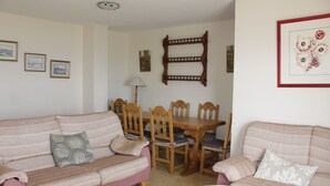 A living room with a pink sofa, a dining table with chairs, and a glass coffee table. - Xeracsol I 5º, Solo Familias! (Xeraco Playa)