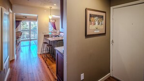 Un couloir avec un plancher en bois, un coin repas avec une table et des chaises, et un tableau encadré au mur.