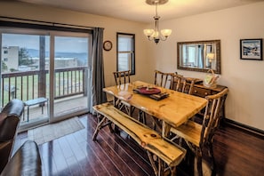 Zona pranzo con tavolo e sedie in legno, un lampadario e vista attraverso una porta scorrevole in vetro.