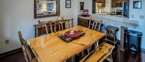 A dining area with a wooden table and benches, a kitchen with a microwave and stove, and a mirror above the counter.