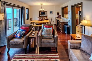 A living room with leather sofas, a wooden coffee table, and a dining area with a wooden table and chairs.