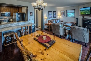 A modern kitchen with a granite countertop, stainless steel appliances, and a wooden dining table with a red placemat.
