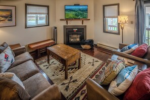 A cozy living room with a fireplace, comfortable seating, and a television mounted above it.
