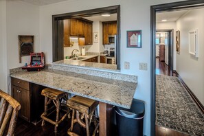 A kitchen with granite countertops, a built-in oven, and a bar area with stools.