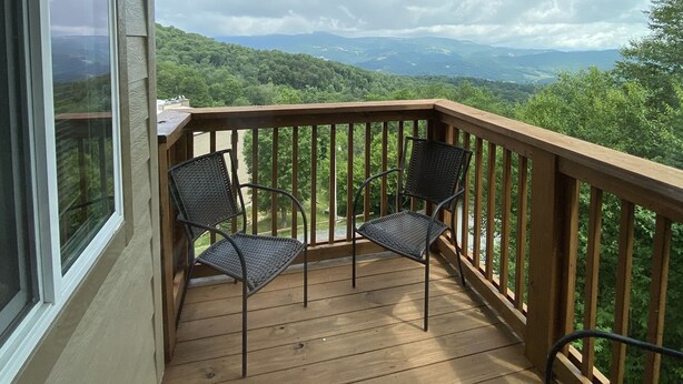 Terraza de madera con dos sillas y vista a un paisaje montañoso.