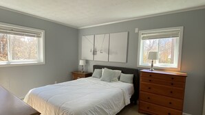 A bedroom with a bed, a dresser, a nightstand, and a wall-mounted lamp. - Sugar Ski Comfort Two Bedroom - Unit 631 (Sugar Mountain)