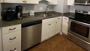 A kitchen with white cabinets, a stainless steel dishwasher, a microwave, and an oven. - Sugar Ski Comfort Two Bedroom - Unit 631 (Sugar Mountain)