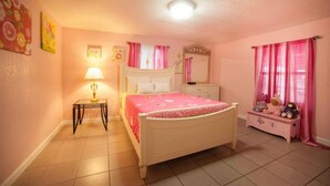 Een slaapkamer met een bed, nachtkastjes, een lamp, een kaptafel en een raam met gordijnen.