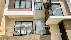 Un moderno edificio de apartamentos con varios balcones, grandes ventanales y una puerta visible con el número 16.