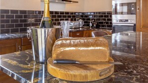 Une cuisine avec un pain, une bouteille de champagne et un couteau posés sur un plan de travail en marbre.