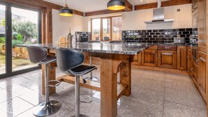Une cuisine moderne dotée d’un plan de travail en marbre, de meubles en bois et de deux luminaires suspendus.
