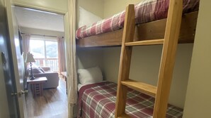 Une chambre avec un lit superposé, une échelle en bois, un bureau et une chaise.