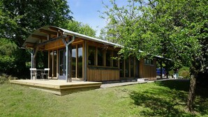 Una cabaña moderna de madera con porche cubierto y ventanas amplias.