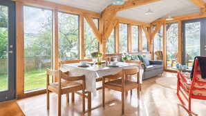 Un comedor amplio con una mesa y sillas de madera, ventanas grandes y vistas al exterior.