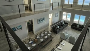 A spacious multi-level living area with a dining area, large windows with ocean views, and modern decor.