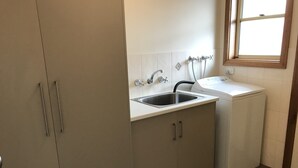 Una cocina compacta con un lavamanos, lavadora y armarios.