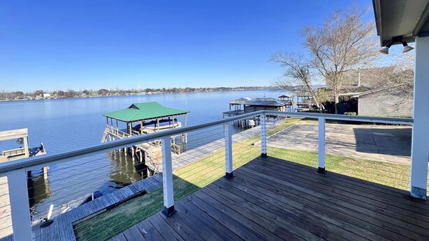 Un muelle de madera con vistas a un lago, un embarcadero y una construcción con techo verde.