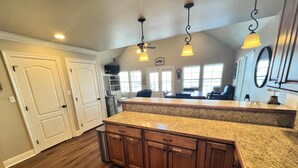 Cocina con gabinetes de madera, encimeras de granito e iluminación colgante.