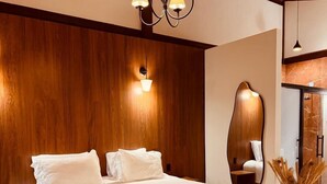 Un dormitorio moderno con una cama grande, un banco, techo de madera y un espejo montado en la pared.
