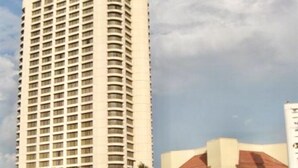 A tall hotel with a modern design, featuring a large entrance and a water body in the foreground.