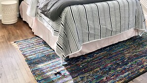 A bedroom with a large bed, a chandelier, and a colorful rug.