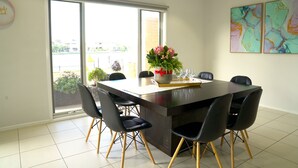 Uma sala de jantar moderna com uma mesa grande, cadeiras pretas e um vaso de flores.