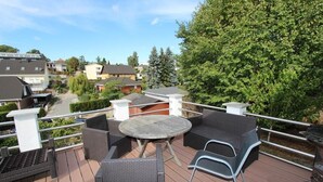 Een terras met buitenmeubilair, waaronder een ronde tafel en stoelen, omringd door een hekwerk.