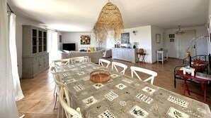 Un amplio espacio habitable con una mesa de comedor, sillas, un sofá y una cocina al fondo.