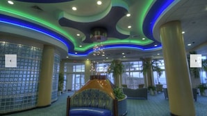 A lobby with a curved seating area, large windows, and a decorative ceiling with green and blue lighting. - 1 Bd Condo, Wide Open Ocean F U N! Atlantic_1BD (Daytona Beach)