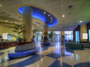 Welcome to our lobby, featuring a spacious area with a checkered floor, columns, and a reception desk.